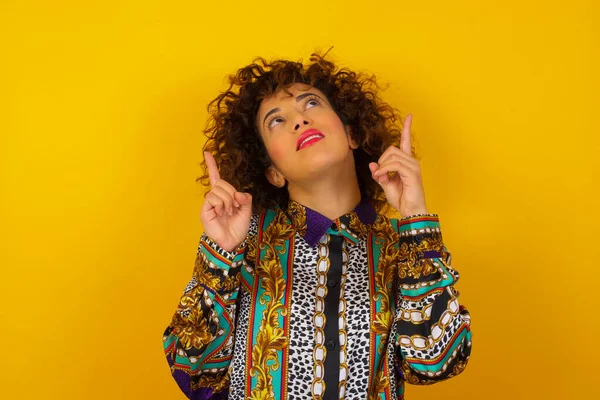 Parlak makyajlı, renkli tişörtlü başarılı bir Arap kadının işaret parmağıyla işaret ederek boş bir fotokopi duvarında şok edici bir şey gösterdiği yatay bir görüntü..