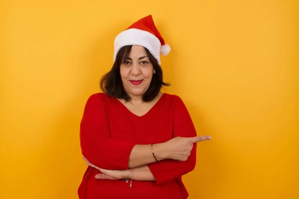 Aufgeregte Frau Mittleren Alters Mit Weihnachtsmütze Zeigt Fröhlich Zur Seite — Stockfoto