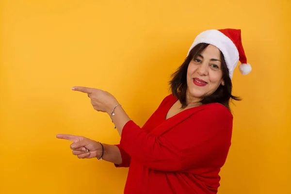 Positiv Attraktive Arabische Frau Mittleren Alters Mit Weihnachtsmütze Zeigt Mit — Stockfoto