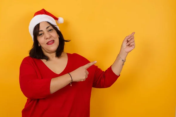Hübsche Arabische Frau Mittleren Alters Trägt Weihnachtsmütze Mit Positivem Gesichtsausdruck — Stockfoto