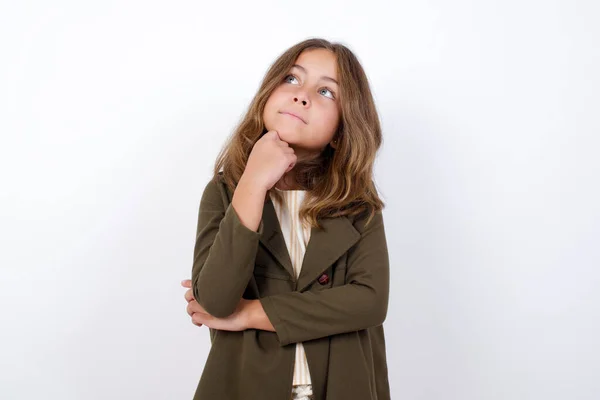 白い背景を見上げる緑のコートを着ている美しい小さな女の子 — ストック写真