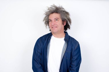 Gizemli bir gülümsemeyle yukarı bakan gizemli erkek portresi. Yakışıklı, gülümseyen adam beyaz duvara bakıyor..