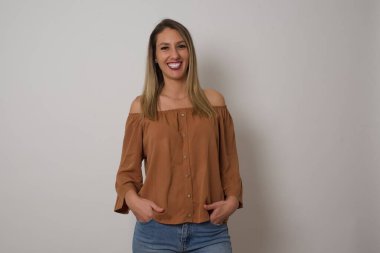 Beyaz duvarın önünde el ele tutuşurken kendinden emin bir ifadeyle gülümseyen çekici bir kadının portresi..