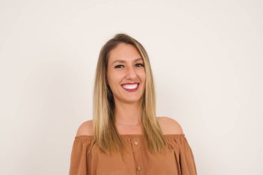 Hoş görünümlü beyaz bir kadının yatay portresi. Uzun, güzel saçları var. Kameraya mutlu bir şekilde bakıyor..