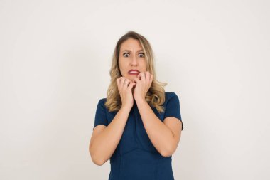 Mavi elbise giyen güzel beyaz kadın beyaz arka plandan korkuyor..  