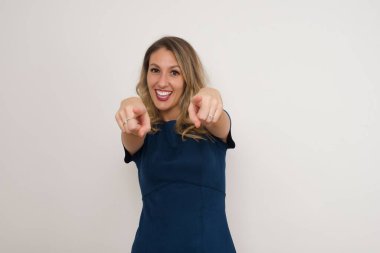 Güzel beyaz kadın parmaklarıyla işaret ediyor. Gri arka planda duruyor. Reklam kavramı.