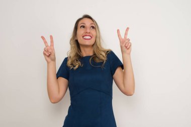 Zafer işaretleriyle güzel beyaz kadın. Gri arka planda duruyor. Reklam kavramı.