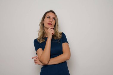 Kafkasyalı güzel bir kadın düşünüyor ve başka tarafa bakıyor. Gri arka planda duruyor. Reklam kavramı.