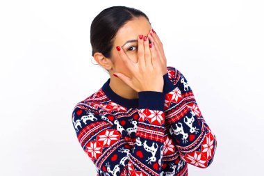   Elleriyle süveter giyen ve bir gözü parmaklarının arasında dışarı bakan genç bir kadın. Bir şeyden ya da birinden korktun mu?. 