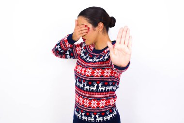   Süveter giyen Arap kadın avuçla gözlerini kapatıyor ve dur hareketi yapıyor, saklanmaya çalışıyor. Bana bakma, görmek istemiyorum, utanıyorum ya da korkuyorum.. 