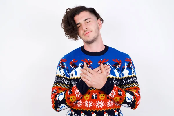 Young Caucasian Man Wearing Sweater Closes Eyes Keeps Hands Chest — Stock Photo, Image