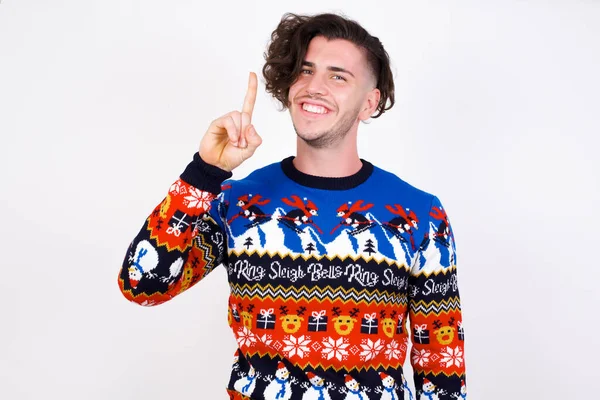 若い白人男性はセーターを着て自信を持って幸せに微笑んでいる間指ナンバー1を指で指で指を指さす — ストック写真