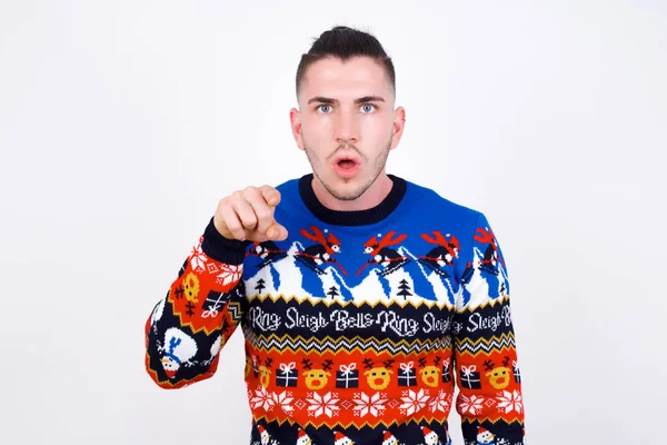 Schokkende Blanke Man Draagt Kersttrui Tegen Witte Muur Wijst Naar — Stockfoto