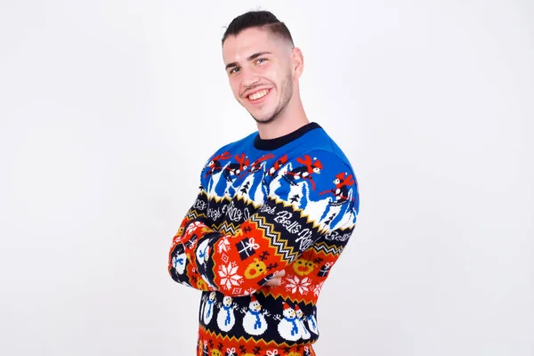 腕が交差した白い壁に対してクリスマスセーターを着用した陽気な白人男性のイメージ カメラを見たり笑ったり 信頼のコンセプト — ストック写真