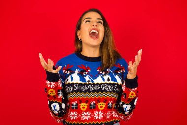 Beyaz kadın Noel süveteri giyip kırmızı duvara yaslanmış ağlıyor ve çığlık atıyordu. İnsani duygular, yüz ifadesi kavramı. Çığlık, nefret, öfke.