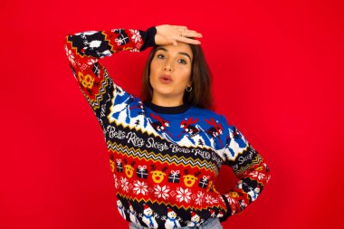 Beyaz kadın, Noel süveteri giyip kırmızı duvara yaslanmış. Alnını elle siliyor. Felaketi önlediği için rahatladığını ifade ediyor. Yeterince yakındı.