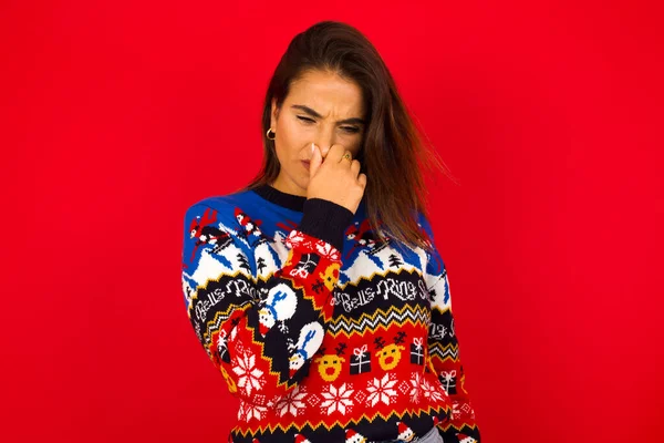 Caucasian Woman Wearing Christmas Sweater Red Wall Holding His Nose — Stock Photo, Image