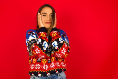 Genç, beyaz bir kadın, kırmızı duvara karşı Noel süveteri giyiyor. Mutsuz bir ifadeyle ellerini tutuyor. Hayvanlarla ilgili hüzünlü bir film izliyor ve ağlamamaya çalışıyor..