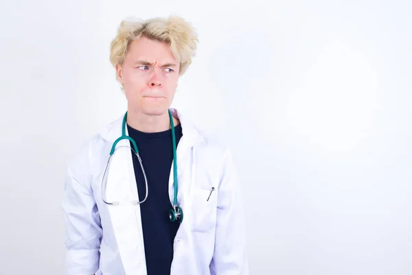 Έκπληκτος Νεαρός Όμορφος Καυκάσιος Γιατρός Φορώντας Λευκό Παλτό Καμπύλες Χείλη — Φωτογραφία Αρχείου