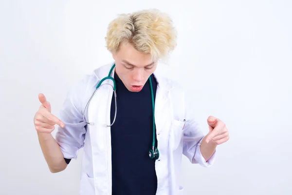 Εντυπωσιασμένος Νεαρός Όμορφος Καυκάσιος Γιατρός Φορώντας Λευκό Παλτό Δείχνει Προς — Φωτογραφία Αρχείου