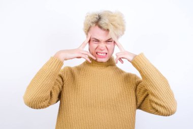 Beyaz arka plana karşı duran beyaz saçlı yakışıklı beyaz adam ciddi bir bakışla bir fikir üzerinde yoğunlaşıyor, her iki işaret parmağıyla alnını işaret ederek düşünüyor..