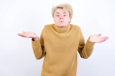 Kafası karışmış, beyaz arka planda duran, kolları açık, omuzlarını silkeleyip 