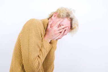 Beyaz arka planda duran beyaz saçlı yakışıklı beyaz adam elleriyle yüzünü örtüyor ve bir gözü parmaklarının arasında dışarı bakıyor. Bir şeyden ya da birinden korktun mu?.