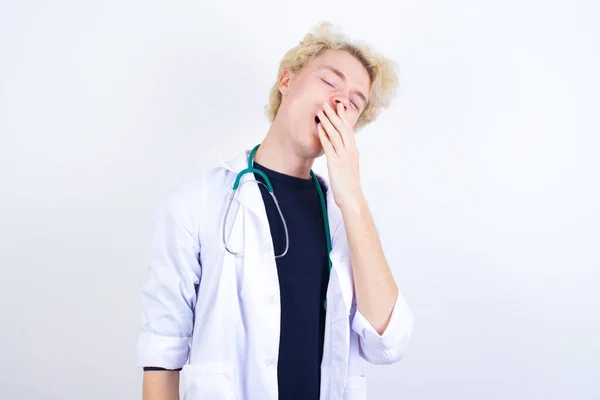 Jovem Médica Loira Sonolenta Casaco Branco Estetoscópio Bocejando Com Cabelos — Fotografia de Stock