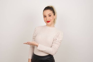 Pozitif memnun dişi der ki: Vay be, ne kadar heyecan verici, hayret verici bir ifade, boş uzayda bir şey gösteriyor, açık elle izole edilmiş gri arkaplan üzerinde. Reklam kavramı.