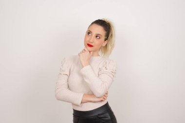 Düşünceli gülümseyen kızın portresi elini çenesinin altında tutuyor, yan bakıyor, ilgi çekici bir şey düşünüyor ya da merak ediyor, sıradan giyinmiş, karar verme kavramını benimsiyor..