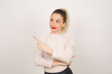 Kamerada poz veren güzel esmer bir kadın. Alengirli bir bakışla ve el kol hareketleriyle. Bayan tasarımcı, işaret parmağıyla harika bir ürün sunuyor. Hareket kavramı.