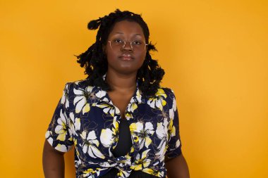  Çekici, başarılı, güzel, Afro-Amerikan bir kadının portresi. Gözlüklü, kendinden emin bir ifadeyle gülümseyen, el ele tutuşan, gri duvarın karşısında duran..