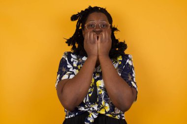 Endişe. Güzel, Afro-Amerikan bir kadının kavramsal görüntüsü. Elleriyle ağzını kapatan gözlük takıyor. 