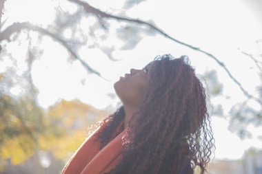 Güz parkında kazak ve eşarp giyen güzel Afro-Amerikan bir kadın.   