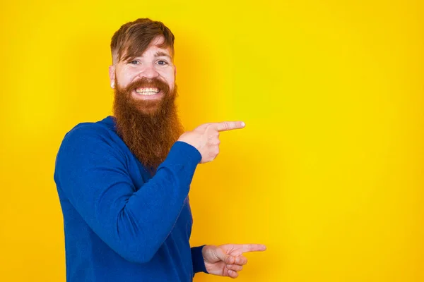 ハンサムな赤毛のひげを被った白人男性が黄色い壁の点に立って 口を開けた驚くような表情で 驚くべきことを示しています 広告コンセプト — ストック写真