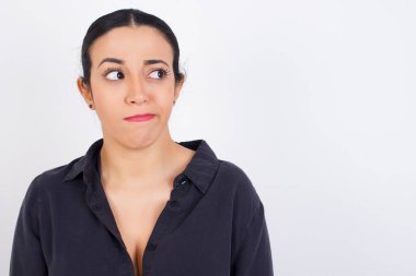 Şaşırmış genç iş kadını elbisesi kıvrımlı dudakları var ve endişeli görünüyor, önünde korkunç bir şey görüyor..