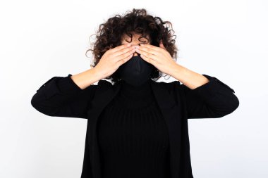 Tıbbi maske takan beyaz bir kadın iki eliyle gözlerini kapatıyor. Hiçbir şey görmek ya da utanmak istemiyor. İnsani duygular tepki verir.
