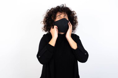 Bu sinir bozucu sesi çıkarmayı kes! Mutsuz, stresli, tıbbi maske takan, endişeli yüz ifadeleri takan, kulakları parmaklarıyla tıkayan, gürültüden rahatsız olan beyaz kadın..