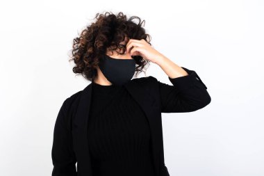Çok üzgün, tıbbi maske takan beyaz bir kadın burnuna dokunuyor, ağlamak istiyor, stresli bir ilişkisi var ya da işiyle ilgili sorunları var.