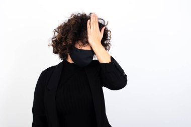 Hüsrana uğramış beyaz kadın, tıbbi maske takıyor. Alnına elele tutuşuyor. Depresyona giriyor..