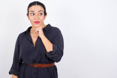 Beyaz stüdyo geçmişine karşı gri elbise giyen, güzel, hayalperest genç bir Arap kadın. Hoş bir ifadeyle yan bakıyor, elini çenesinin altında tutuyor, hoş bir şeyler düşünüyor..