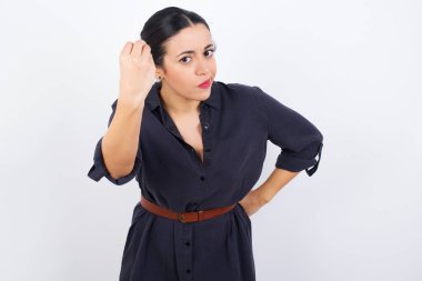 What the hell are you talking about. Shot of frustrated Arab woman wearing dress against white studio background  gesturing with raised hand doing Italian gesture, frowning, being displeased and confused with dumb question.