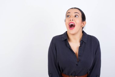 Şaşırmış genç, güzel, Latin bir kadın elbise giyiyor omuzlarını silkiyor, yana bakıyor, mutlu ve heyecanlı. Ani tepkiler konsepti.