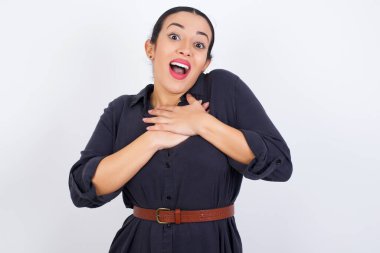 Mutlu gülümseyen genç, güzel, elbise giyen Latin kadının elleri göğsüne yakın. İnsani duygular, gerçek duygular ve yüz ifadesi kavramı.