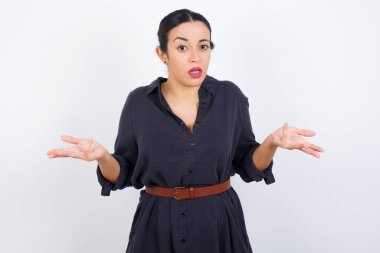 Genç, güzel, Latin bir kadın elbise giyiyor. Omuzlarını silkiyor..