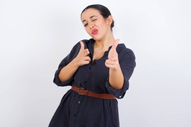 Hey sen, bang. Neşeli ve karizmatik güzel bir kadın, kameraya mutlu ve küstah bir şekilde göz kırpıyor ve silah doğrultuyor..