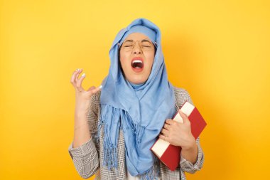 Çığlık, nefret, öfke. Ağlayan öfkeli genç Müslüman kadın tesettüre sarılmış kitap çığlıkları, insan duyguları konsepti..