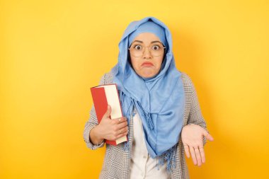 Kafası karışmış ve kafası karışık genç müslüman bir kadın, elini uzatıp tesettüre girmiş, omuzlarını silkip: 