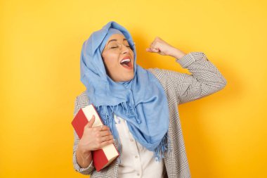 Çekici, tesettürlü genç Müslüman kadın zaferi kutluyor yumruğuyla havaya yumruk atıyor ve parlak bir tebessümle arka planda fotokopi çekiyordu..