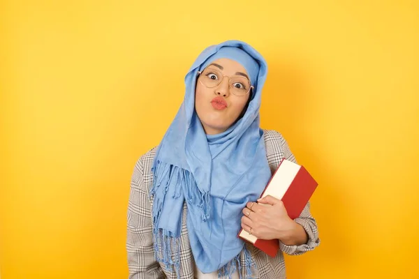 容光焕发的年轻的穆斯林女子头戴头巾 嘴边挂着要亲吻某人的笑脸 脸上带着喜色 在空白的工作室背景下站立 美的概念 — 图库照片